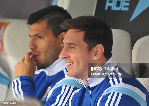 Lionel Messi and Sergio Aguero of Argentina watch the game from the substitutes bench during a FIFA friendly match between Argentina and Slovenia at...