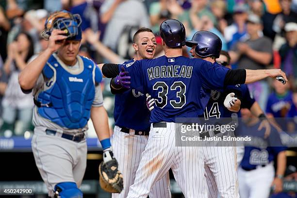 Justin Morneau of the Colorado Rockies celebrates with Troy Tulowitzki and Josh Rutledge after scoring the winning run in the 10th inning on a triple...