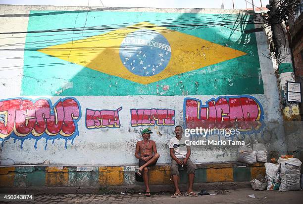 People sit beneath a Brazil flag painted in the occupied Complexo da Mare, one of the city's largest 'favela' complexes, on June 7, 2014 in Rio de...