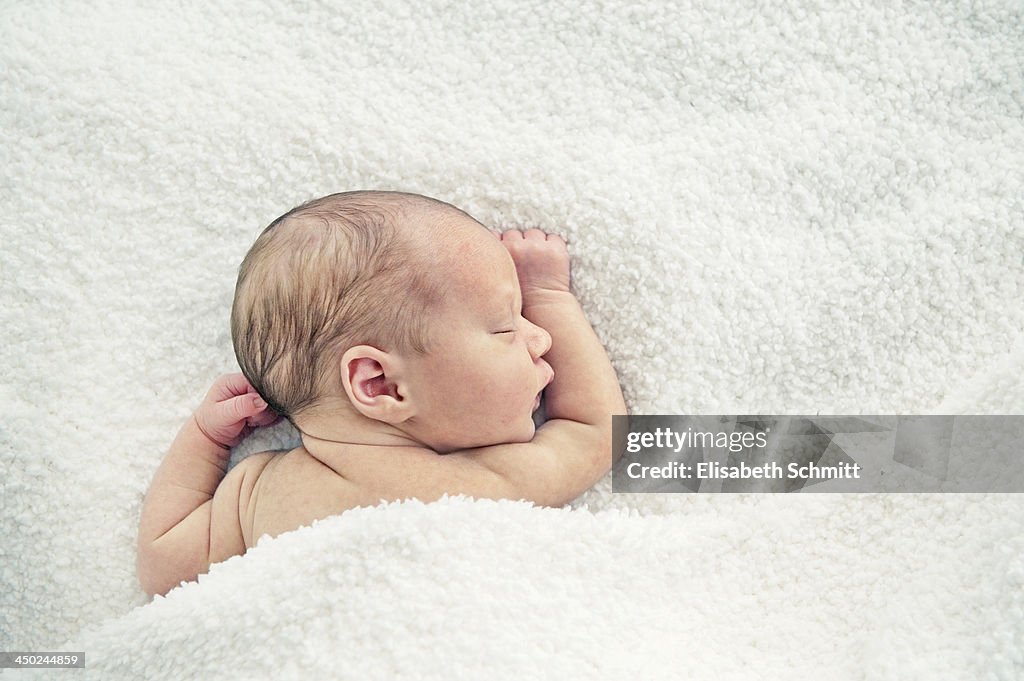 Newborn baby sleeping under blanket