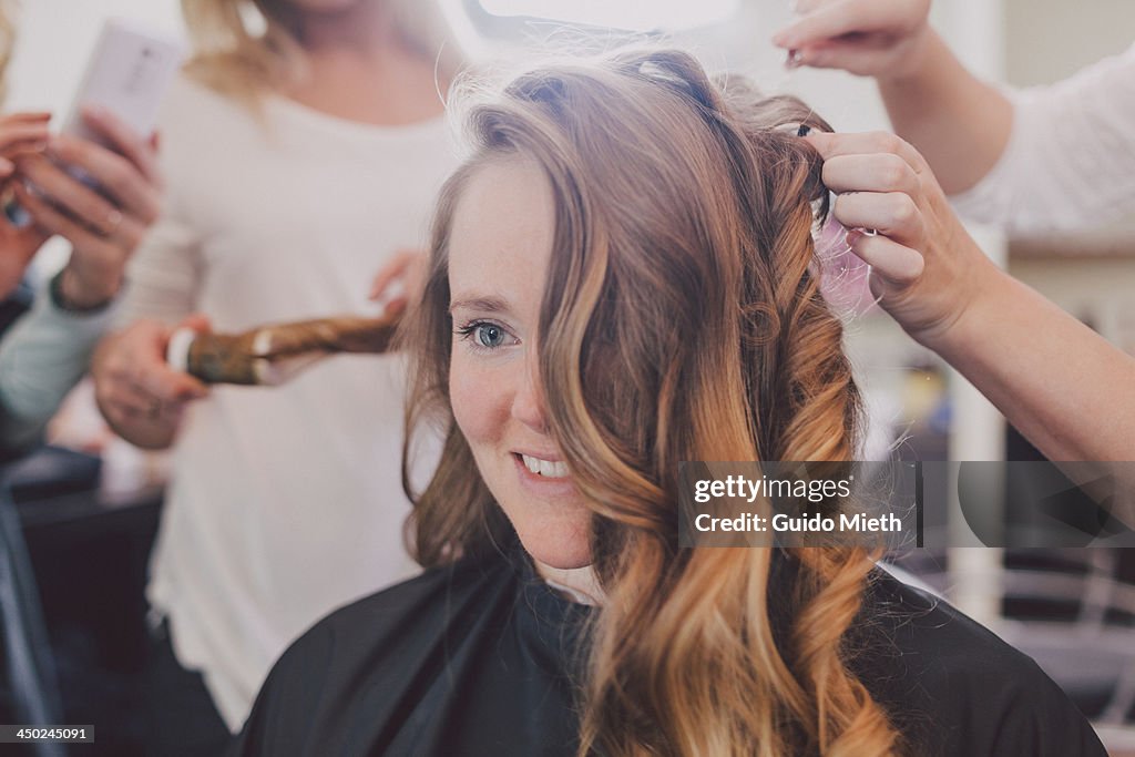 Woman with hairdressers around.