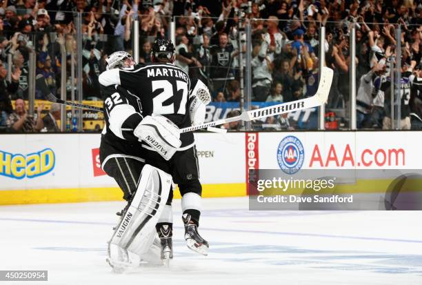 Goaltender Jonathan Quick of the Los Angeles Kings celebrates with Alec Martinez after Dustin Brown scored the overtime goal to defeat the New York...