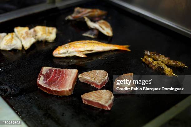 Pieces of red tuna and other fishes are cooked on a griddle inside El Campero Restaurant during the end of the Almadraba tuna fishing season on June...