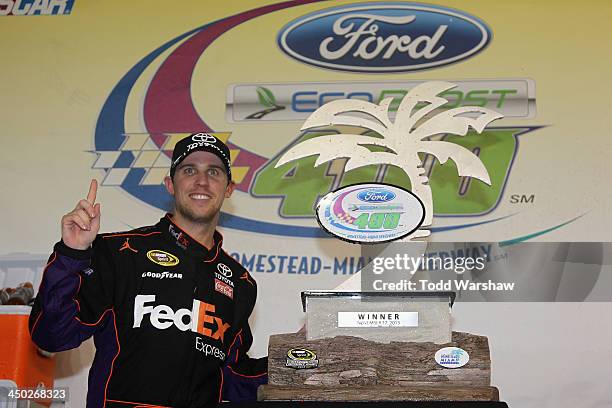 Denny Hamlin, driver of the FedEx Express Toyota, poses with the winner's trophy after winning the NASCAR Sprint Cup Series Ford EcoBoost 400 at...