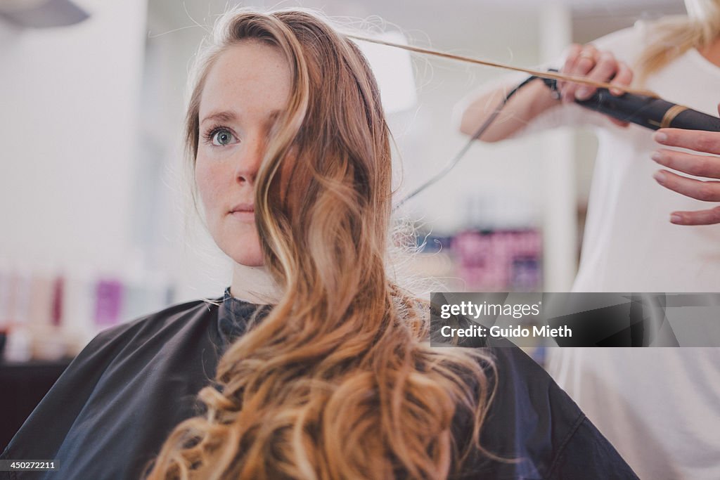 Woman getting curls in coiffeur studio