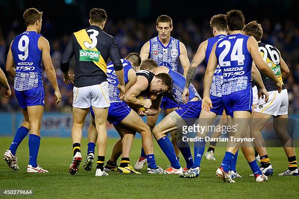 Nathan Foley of the Tigers is tackled during the round 12 AFL match between the North Melbourne Kangaroos and the Richmond Tigers at Etihad Stadium...