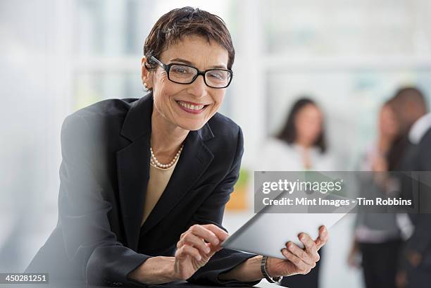 an office interior. a woman in a black jacket using a digital tablet. - departamento de estado de eeuu - fotografias e filmes do acervo