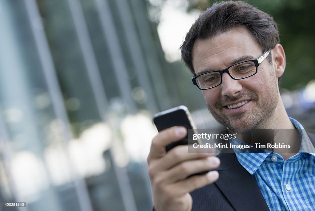 Business people in the city. Keeping in touch on the move. A man using his smart phone.