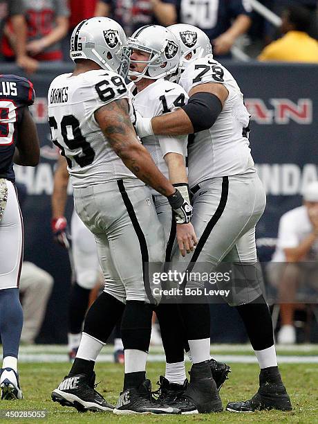 Matthew McGloin of the Oakland Raiders is congratulated by Tony Pashos and Khalif Barnes after throwing a pass for a touchdown against the Houston...