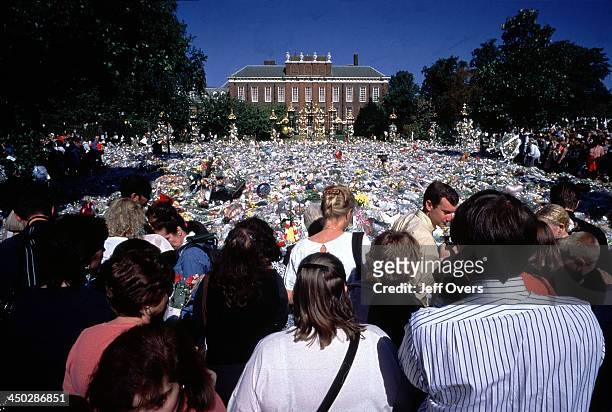 Kensington Palace mourners after the death of Diana, Princess of Wales - People with backs turned from camera surround the floral tributes left in...