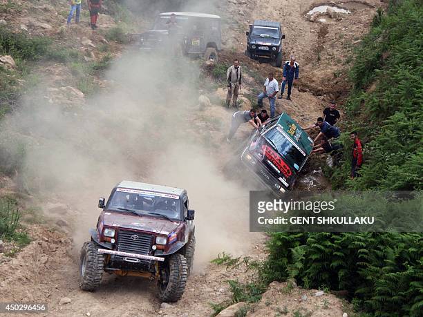 Drivers and mechanics help to put back on the road a four-wheel car during the tenth Albania's Rally near the village of Petrela on June 8, 2014....