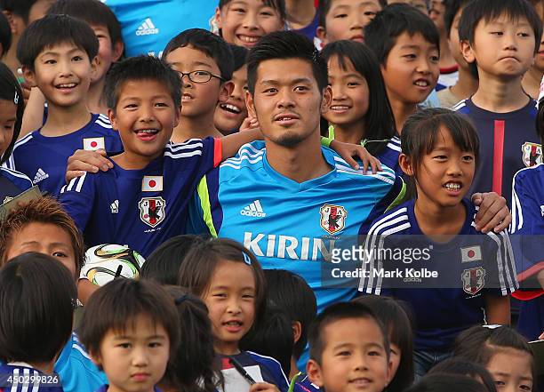 Hotaru Yamaguchi of Japan poses with children as the team pose for a group photo with children from the local community during a Japan training...