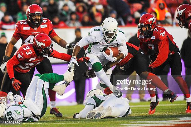 Kory Sheets of the Saskatchewan Roughriders splits the defense of Eric Fraser and Chris Randle of the Calgary Stampeders during a CFL game at McMahon...