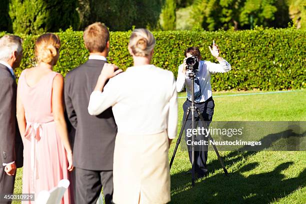 family posing while man photographing them at garden wedding - wedding photographer stock pictures, royalty-free photos & images