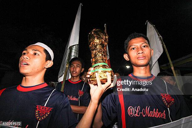 Students of Daarun Najah Islam Boarding School hold replica of World Cup trophy after playing fire football in Semarang, Indonesia on 7 June, 2014....