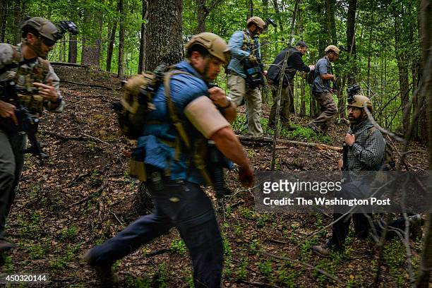 During a training exercise, special agents escort a make-believe consular general, 2nd from R in back, through the woods to a helicopter landing zone...
