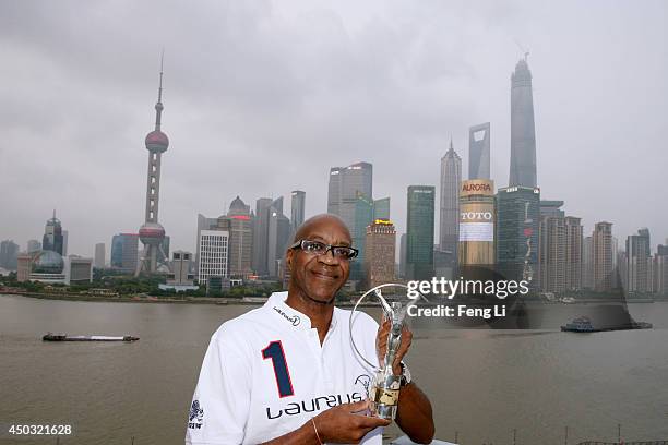 Laureus Academy Chairman Edwin Moses poses with the Laureus trophy in front of the skyscrapers of Pudong Lujiazui Financial District on June 8, 2014...