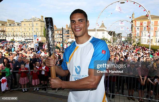 In this handout image provided by Glasgow 2014 Ltd, Olympic boxer Anthony Ogogo carries the Queen's Baton along the Lowestoft Seafront on June 9,...