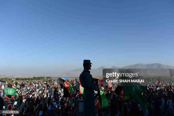 An Afghan policeman keeps watch as supporters of presidential candidate Abdullah Abdullah cheer during an election campaign rally in Paghman district...