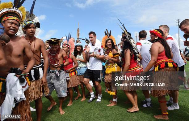 Germany's forward Miroslav Klose dances with native Brazilians on the sidelines of a training session of Germany's national football team in Santo...