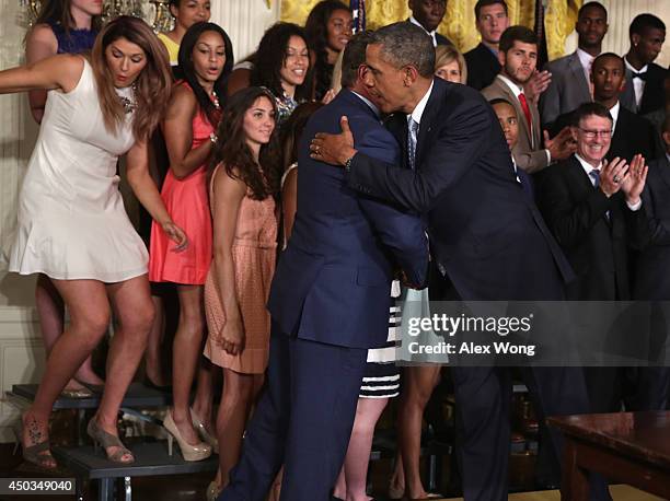 President Barack Obama hugs head coach Geno Auriemma as center Stefanie Dolson of the University of Connecticut women's basketball team slips off the...