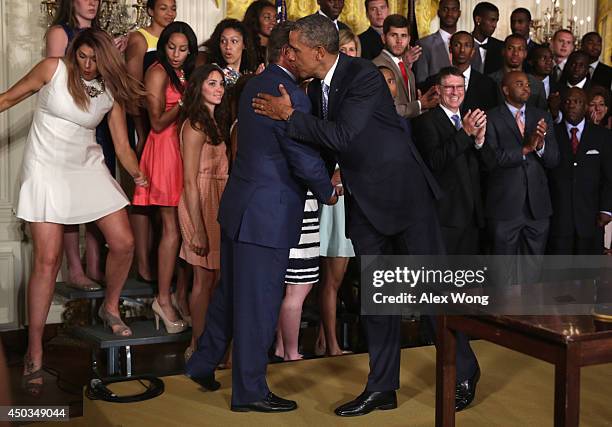 President Barack Obama hugs head coach Geno Auriemma as center Stefanie Dolson of the University of Connecticut women's basketball team slips off the...