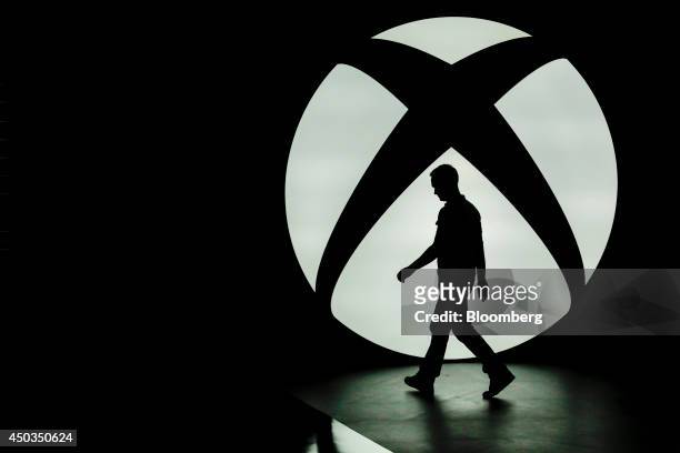 The silhouette of Ralph Fulton, design director for Forza Horizon at Playground Games, is seen walking past the Microsoft Corp. Xbox One logo uring a...