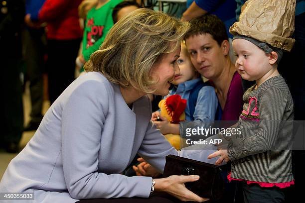 Belgium's Queen Mathilde talks to a child on November 18, 2013 during a visit to the UZ Leuven hospital in Leuven, part of the aloud reading week,...