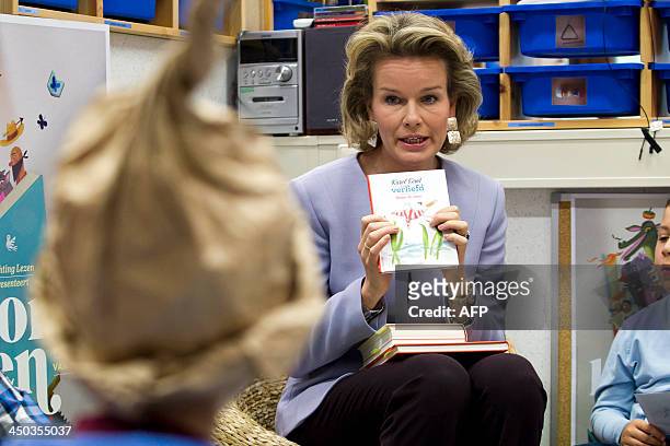 Belgium's Queen Mathilde shows a book on November 18, 2013 during a visit to the UZ Leuven hospital in Leuven, part of the aloud reading week,...