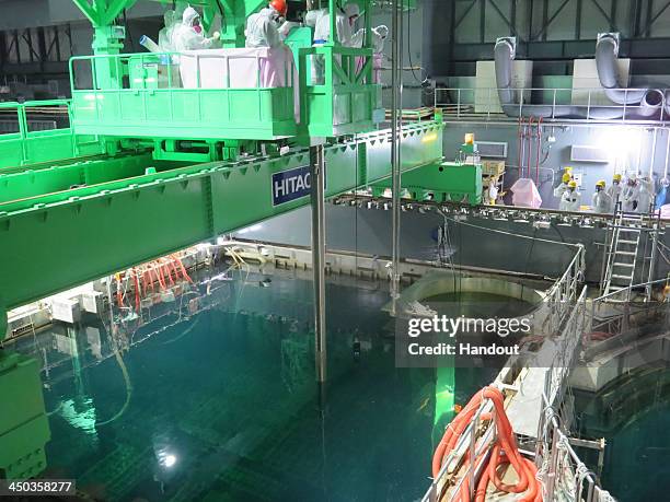 In this handout image provided by Tokyo Electric Power Co, workers remove nuclear fuel rods from a pool at No. 4 reactor of the Fukushima Daiichi...