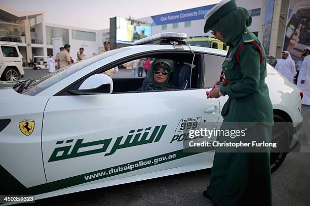 Female Emerati police officers chat as they stand next to their Ferrari supercar during the Dubai Airshow on November 18, 2013 in Dubai, United Arab...