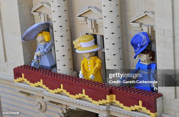 Figures of Camilla, Duchess of Cornwall, Queen Elizabeth II, Catherine, Duchess of Cambridge stand outside a LEGO Buckingham Palace wearing designer...