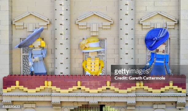 Figures of Camilla, Duchess of Cornwall, Queen Elizabeth II, Catherine, Duchess of Cambridge stand outside a LEGO Buckingham Palace wearing designer...