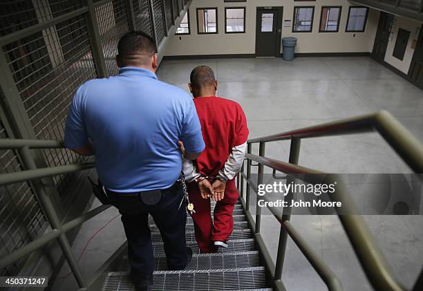 Guard escorts an immigrant detainee from his 'segregation cell' back into the general population at the Adelanto Detention Facility on November 15,...