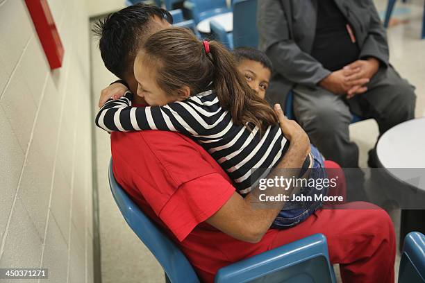 An immigrant detainee holds his children during a family visitation visit at the Adelanto Detention Facility on November 15, 2013 in Adelanto,...