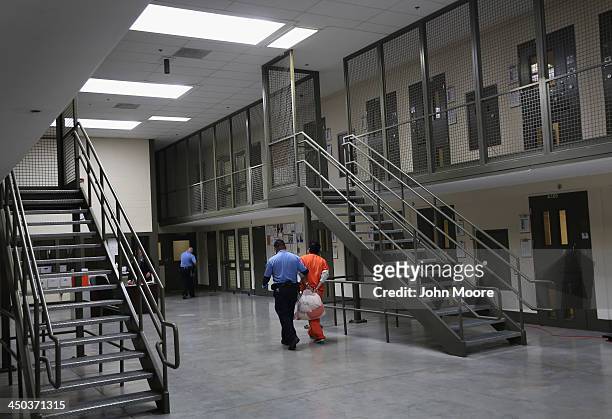 Guard escorts an immigrant detainee from his 'segregation cell' back into the general population at the Adelanto Detention Facility on November 15,...