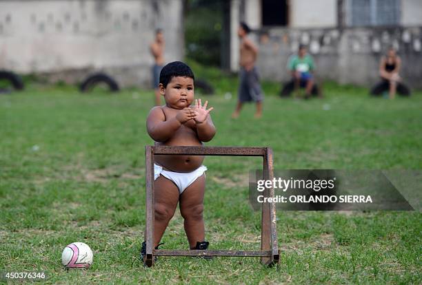 Toddler looks at garifuna boys playing football in a beach of El Triunfo de la Cruz community, in the Hondurean Caribbean on June 10, 2014. AFP...