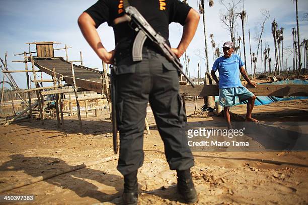Gold miner watches as a National Police officer searches for illegal mining operations in the Amazon lowlands on November 17, 2013 in Madre de Dios...