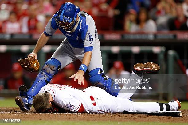 Drew Butera of the Los Angeles Dodgers checks on Zack Cozart of the Cincinnati Reds after he was hit by a pitch in the fifth inning of the game at...