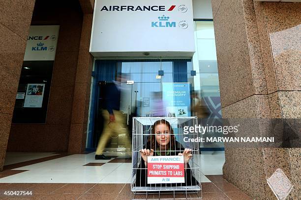 People look at an activist of the People for Ethical Treatment of Animals imprisoned in tiny cage with a banner reading: "Air France, Stop Shipping...