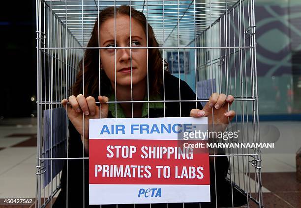 An activist of the People for Ethical Treatment of Animals is seen imprisoned in tiny cage with a banner reading: "Air France, Stop Shipping Primates...