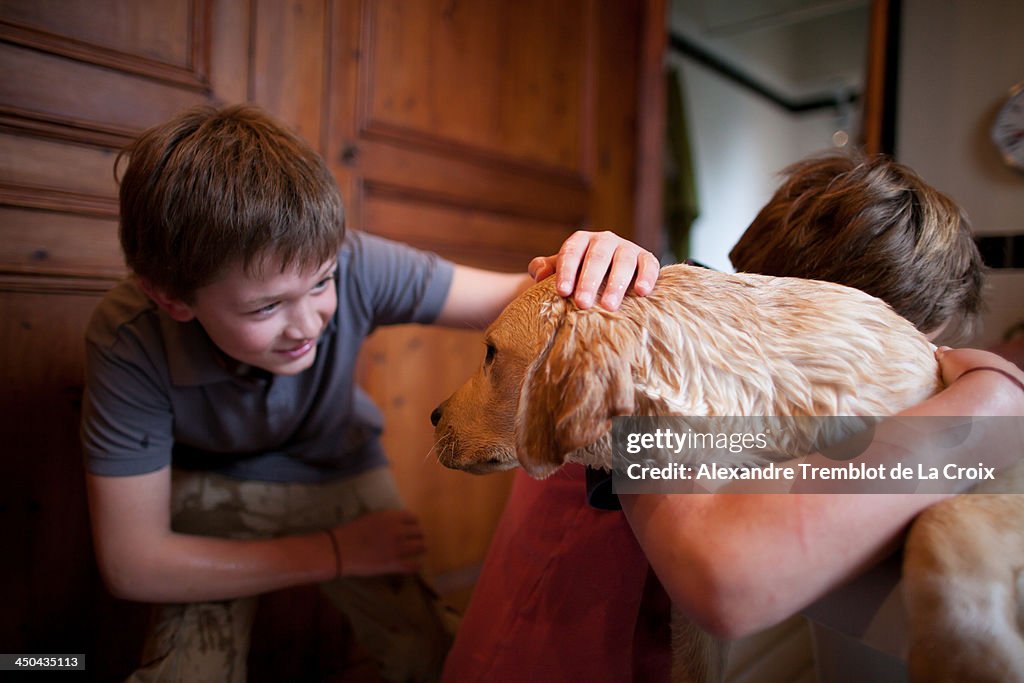 Dog washed by two boys in the bathtub