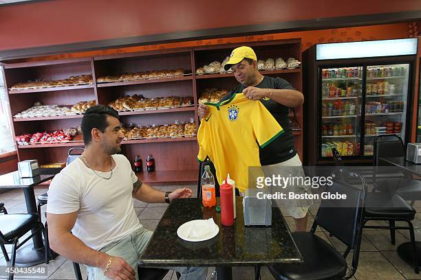 Robson Ramos, right, brings shirt to customer Nick Santos, left, at the Padaria Brasil Bakery in Framingham. Ramos sports store closed from lack of...