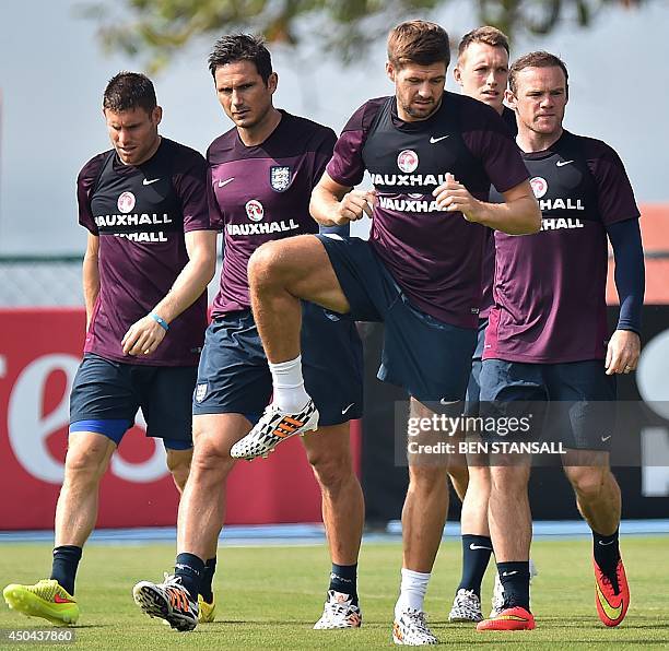England's midfielder Steven Gerrard stretches as England's forward Wayne Rooney and England's midfielder Frank Lampard look on during a training...