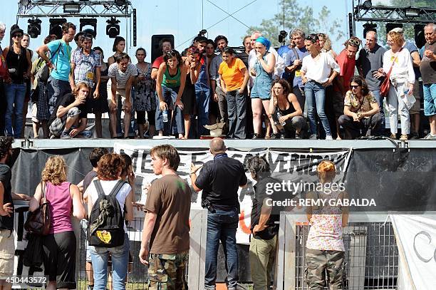 Entertainment industry workers and artists stand next to a banner hanging from a stage reading "MEDEF and Government - No to the agreement and the...