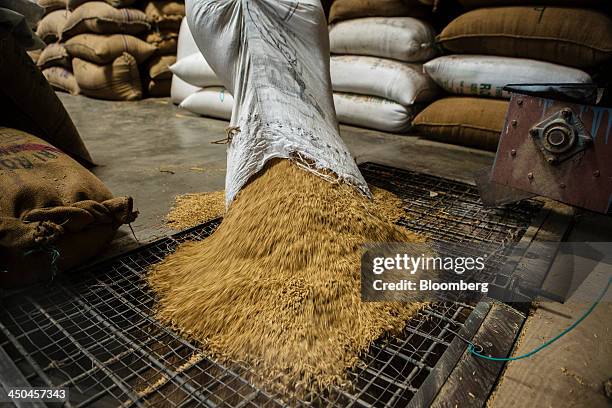 Worker pours a bag of rice grain into a dehusking machine at the KRK Modern Rice Mill in Kothapeta, Tamil Nadu, India, on Thursday, Nov. 14, 2013....