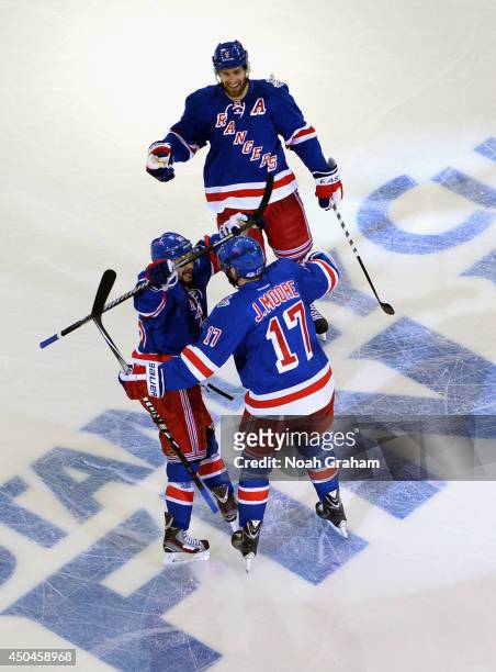 John Moore of the New York Rangers celebrates with Mats Zuccarello and Dan Girardi after a goal scored by Benoit Pouliot in the first period of Game...