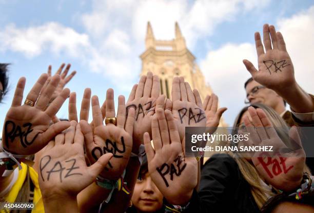 Supporters of Colombian president and presidential candidate Juan Manuel Santos raise their hands with the word "Peace" written on them during a...