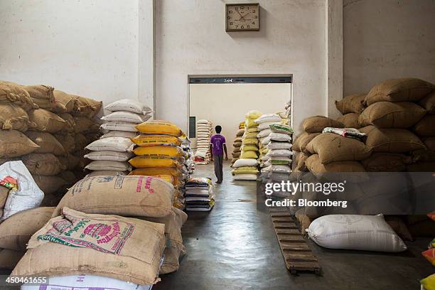 Worker walks past bags of rice in a warehouse at the KRK Modern Rice Mill in Kothapeta, Tamil Nadu, India, on Thursday, Nov. 14, 2013. Record onion...