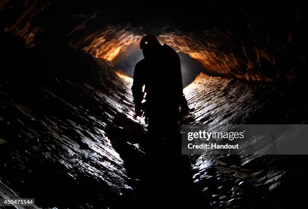 In this undated handout photo a spelunker explores the Riesending cave where an explorer is currently lying injured 1,000 meters below since June 8,...